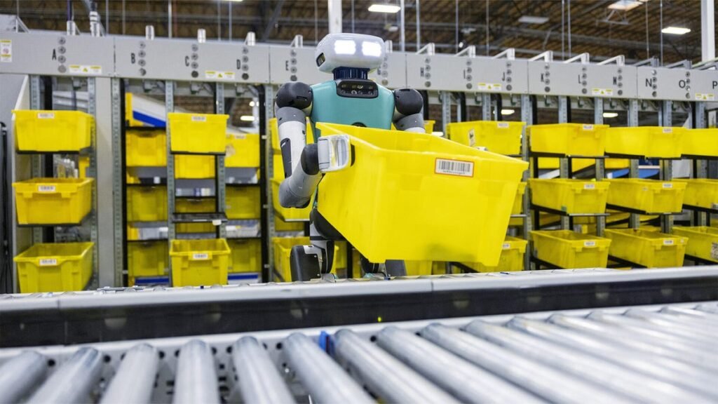 A humanoid robot lifting a yellow bin in a warehouse
